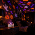 Halloween dynamic projection light casting glowing ghosts, bats and pumpkins on a dark bedroom wall